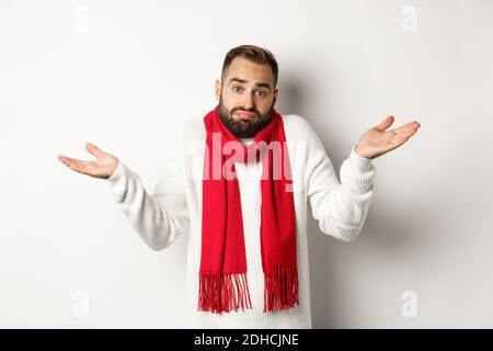 Barbu homme haussant, levant les mains et regardant sans indice, ne sais rien, debout dans le chandail et le sca de noël Banque D'Images