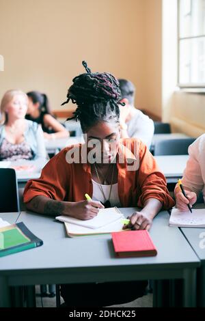 Une jeune femme confiante écrit des notes en classe Banque D'Images