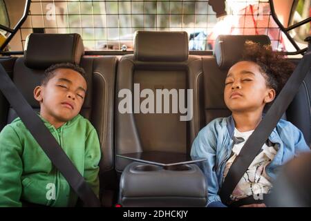 Frères et sœurs fatigués dormant dans la voiture électrique Banque D'Images