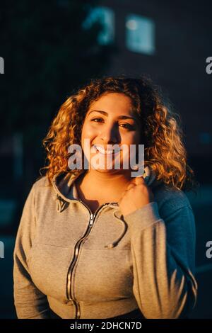 Portrait d'une jeune femme souriante en chemise à capuche au coucher du soleil Banque D'Images