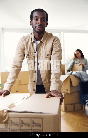 Portrait de jeunes couples ethniques mixtes debout dans le salon de nouveaux boîtiers de retrait de déballage de la maison ensemble Banque D'Images