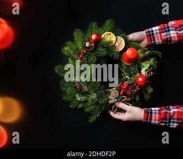 Belle couronne de Noël dans les mains de femme. Décoration intérieure festive. Banque D'Images