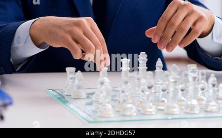 Jeune homme jouant glass chess in office Banque D'Images