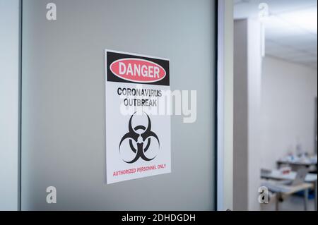 Avis d'alerte papier sur la porte du danger d'éclosion de coronavirus avec symbole de danger biologique et personnel autorisé uniquement Banque D'Images
