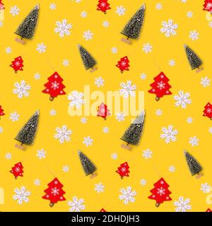 Fond jaune sans couture avec décorations de Noël, flocons de neige blancs, arbres verts artificiels et un arbre de Noël en bois rouge. Banque D'Images