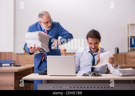 Un jeune homme et un vieux patron brûlent des papiers sur le lieu de travail Banque D'Images