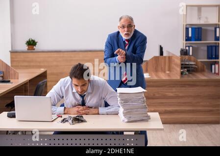 Un jeune homme et un vieux patron brûlent des papiers sur le lieu de travail Banque D'Images