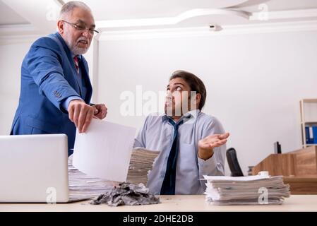 Un jeune homme et un vieux patron brûlent des papiers sur le lieu de travail Banque D'Images