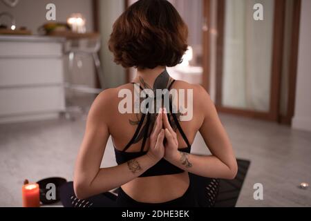 Anonyme tatouée femme claquant les mains derrière le dos tout en méditant à accueil Banque D'Images