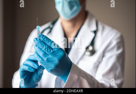 Médecin en pelage blanc tenant la seringue avec le vaccin prêt pour l'injection. Banque D'Images