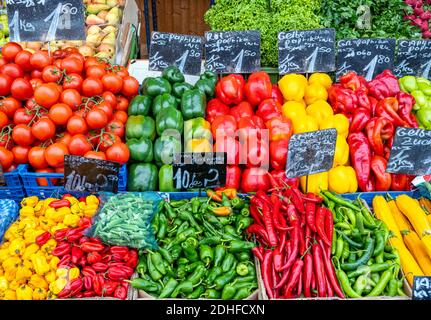 Différents types de poivrons et quelques tomates à vendre à un marché Banque D'Images