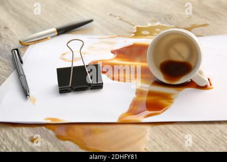 Papeterie, gobelet renversé et café renversé sur une table de bureau Banque D'Images