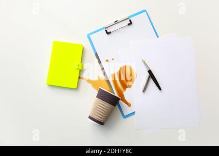 Papeterie, gobelet renversé et café renversé sur une table de bureau Banque D'Images