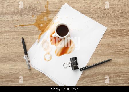 Papeterie, tasse et café renversé sur une table de bureau Banque D'Images