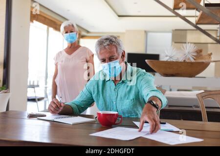 Couple caucasien senior portant des masques dans la cuisine Banque D'Images