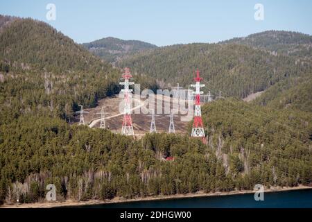 Supports métalliques de lignes électriques aériennes pour l'électricité dans la forêt sibérienne, sur la rive. Banque D'Images