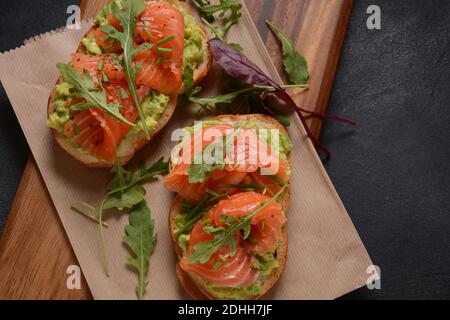 Pain à grains entiers avec pâte d'avocat et saumon, feuilles d'arugula. Banque D'Images