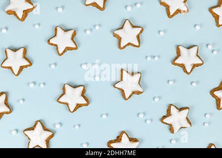 Vue de dessus des biscuits de Noël à la cannelle émaillée en forme d'étoile allemande Appelé 'Zimtsterne' sur fond bleu clair avec des ornements de boule de neige Banque D'Images