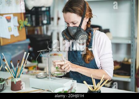 Femme caucasienne mélangeant des couleurs de peinture avec un équilibre vintage à l'intérieur Son studio de poterie créatif - se concentrer sur son oeil Banque D'Images