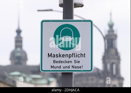 Dresde, Allemagne. 11 décembre 2020. Un panneau indiquant que les masques sont obligatoires est accroché à un lampadaire sur fond de la vieille ville avec le Hausmannsturm (l) et la Katholische Hofkirche (église de la Cour catholique). La Saxe veut encore restreindre la vie publique au vu des chiffres drastiques de l'infection dans l'État libre. Credit: Sebastian Kahnert/dpa-Zentralbild/dpa/Alay Live News Banque D'Images