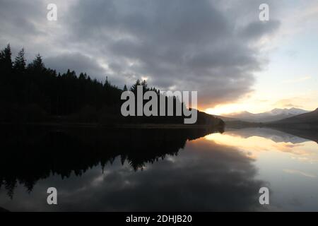 Coucher de soleil sur le Snowdon Horseshoe en travers montrant la neige récente au-delà d'un calme plat Llynnau Mymbyr. Pays de Galles. Photo prise le 5 décembre 2020 Banque D'Images