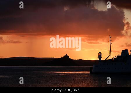 Le calme avant la tempête Alex, alors que le soleil se lève derrière le phare du port de Penzance le premier jour d'octobre. Banque D'Images