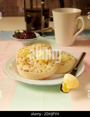 Crumettes grillées traditionnelles au beurre chaud sur une assiette blanche sur une table, avec du beurre fondu prêt à manger. Banque D'Images