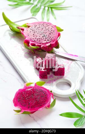 Fruit de dragon rose, pitaya ou pitahaya tranché en cubes. Super-nourriture tendance sur planche à découper blanche. Banque D'Images