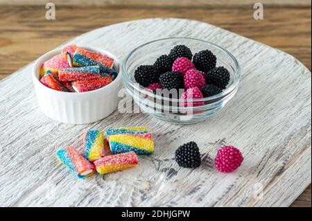 Bonbons à la marmelade à mâcher multicolores dans des bols sur une planche à découper en bois. Banque D'Images