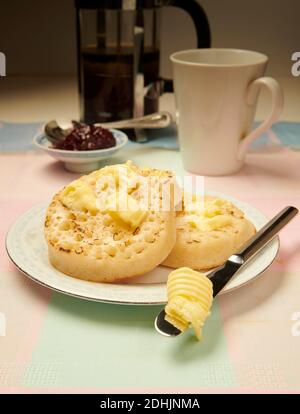 Crumettes grillées traditionnelles au beurre chaud sur une assiette blanche sur une table, avec du beurre fondu prêt à manger. Banque D'Images