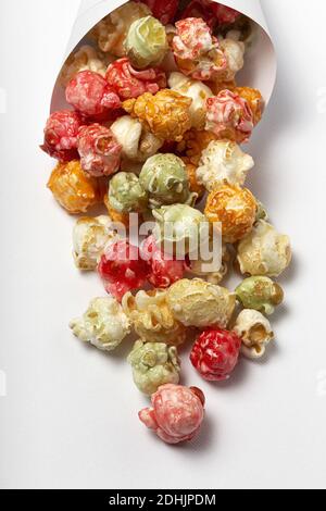 Grand angle de pop-corn savoureux coloré dans le cône en papier placé sur fond blanc en studio Banque D'Images