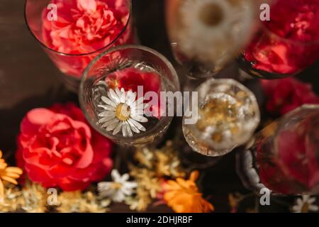 De dessus belle disposition élégante avec différents types de cristal verres et bouteille placés parmi les boutons de fleurs frais assortis sur tableau contre blu Banque D'Images