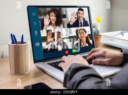 Crop homme d'affaires anonyme assis à table avec ordinateur portable dans le bureau et communiquer avec des collègues multiraciaux par vidéoconférence Banque D'Images