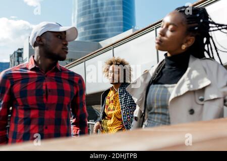 Malheureux jeune homme noir souffrant de l'amour sans demande pendant que la petite amie avoir une conversation sérieuse avec un autre type dans la rue de la ville Banque D'Images