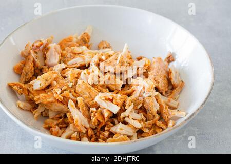 Bol blanc à grand angle avec viande de poulet grillée déchiquetée Pour salade César sur table grise Banque D'Images