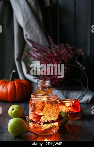 Lanterne d'automne faite d'un pot en verre décoré de feuilles colorées et d'une couronne de bruyère. Bougie à l'intérieur. Banque D'Images