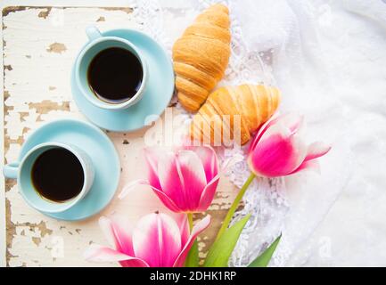 Bonne tasse de café, des croissants et des tulipes roses sur le vieux tableau blanc. Banque D'Images