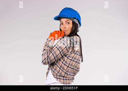 Une femme mécanicien dans un casque tient une clé sur un fond blanc regardant la caméra. Espace latéral pour la publicité Banque D'Images