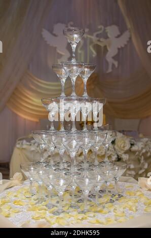 Pyramide des verres à champagne se tient sur une table décorée de pétales de rose, des anges en arrière-plan Banque D'Images