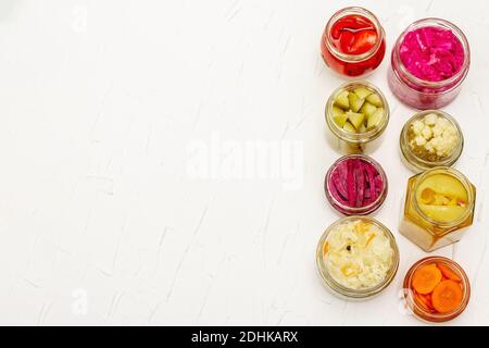 Assortiment de légumes fermentés en pots de verre. Concept de légumes de saison conservés, aliments probiotiques pour un mode de vie sain. Fond maté blanc, à Banque D'Images