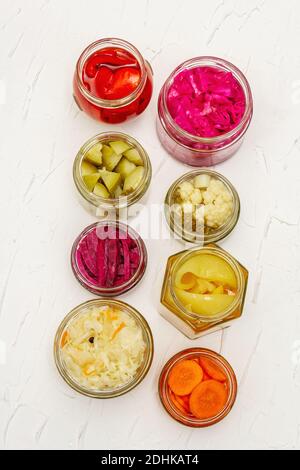 Assortiment de légumes fermentés en pots de verre. Concept de légumes de saison conservés, aliments probiotiques pour un mode de vie sain. Fond maté blanc, à Banque D'Images