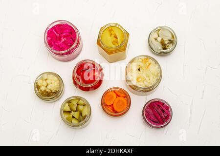 Assortiment de légumes fermentés en pots de verre. Concept de légumes de saison conservés, aliments probiotiques pour un mode de vie sain. Fond maté blanc, à Banque D'Images