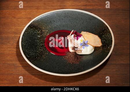 Plat de dessert Panna cotta dans une assiette noire sur une table en bois Banque D'Images