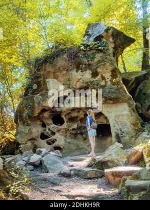 Une fille regarde un rocher avec beaucoup de trous un jour d'été dans la forêt Banque D'Images
