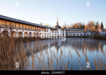 Le monastère de Tikhvin Assomption, la tour sud-ouest du mur du monastère, se reflète dans la glace mince du lac Syrkovo. Hiver gelé sans neige Banque D'Images