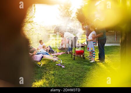 Une grande famille aimante profite d'un pique-nique et attend que le gril soit prêt pour une belle journée d'été. Banque D'Images