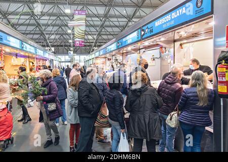 Huelva, Espagne - 11 décembre 2020 : intérieur du marché Mercado del Carmen. Les gens qui achètent des fruits de mer, portant un masque protecteur pour le visage dû au coronavirus COVID-19 Banque D'Images