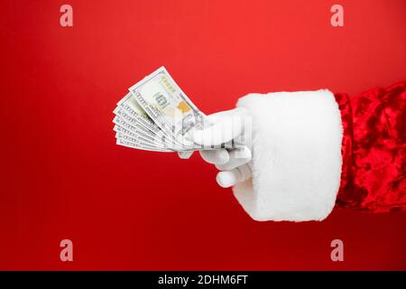Main du Père Noël tenant de l'argent sur fond rouge. Main avec de l'argent. Banque D'Images