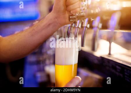 Vue rapprochée de la mise au point des mains du serveur versant de la bière à pression. Banque D'Images