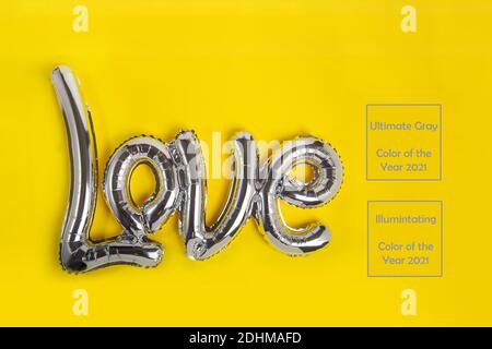 Ballons argentés en feuilles grises sous la forme d'un mot Love sur fond jaune. Bonne Saint Valentin. Concept d'amour. Couleurs tendance de l'année 2021. Copier Banque D'Images